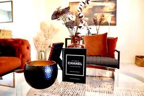 A book titled 'Little Book of Chanel' on a table with a vase of dried flowers and a decorative bowl. - 3 Miles from Hope Mills Lake! 2 acre home with 5 SmartTvs + Self Check (Hope Mills)