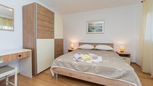 Quarto bem arrumado com cama, mesas de cabeceira, escrivaninha e espelho.