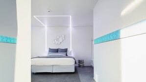 A modern bedroom with a bed, a geometric light fixture, and a patterned rug. - Quarters A2- Luxurious studio (Dunedin)
