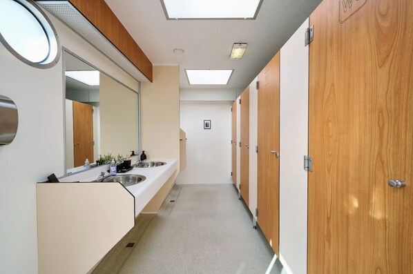 Un baño moderno y limpio con dos lavamanos, un espejo y puertas de madera.