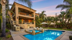 Ein zweistöckiges Haus mit Swimmingpool, Außenbereich und Balkon.