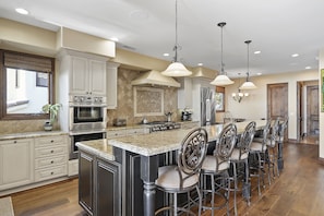 A kitchen with a large island, bar stools, and modern appliances.