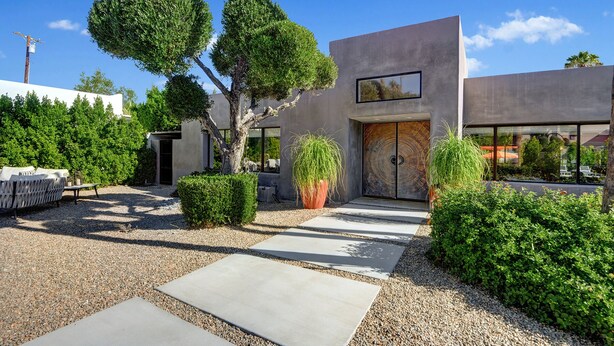 A modern building with a minimalist design, featuring a large glass door and a concrete facade. - Luxury 4BD Oasis: Pool, Spa, Fire Pit, Near It All (Palm Springs)