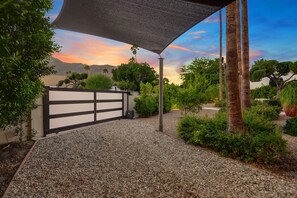 A gravel pathway leading to a gated entrance with a pergola overhead. - Luxury 4BD Oasis: Pool, Spa, Fire Pit, Near It All (Palm Springs)