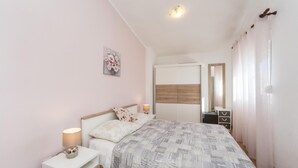 A bedroom with a bed, bedside tables, a nightstand, a mirror, and a door. - Stunning apartment in Pag with WiFi (Pag)