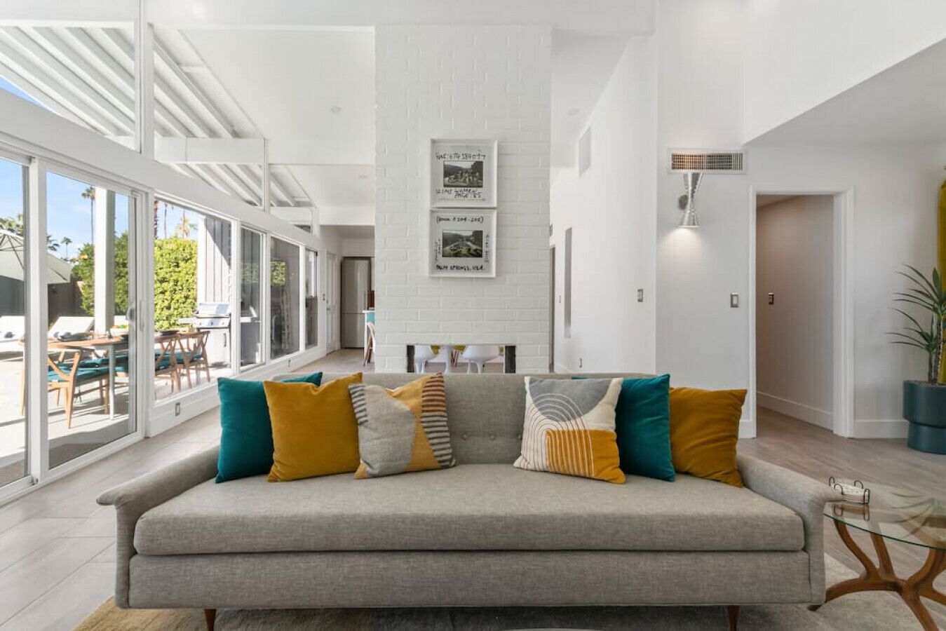 A modern living room with a grey sofa, colorful cushions, and a glass coffee table.