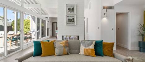 A modern living room with a grey sofa, colorful cushions, and a glass coffee table.