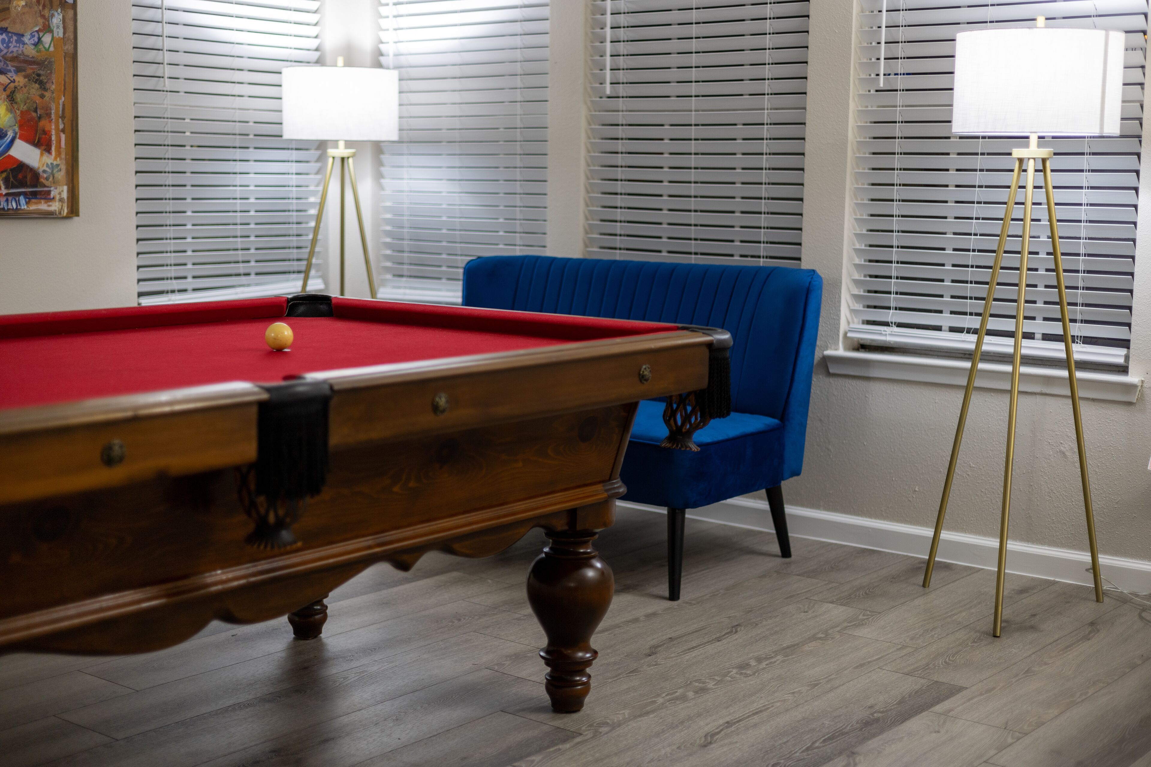 A pool table with a blue chair and a lamp near the window.
