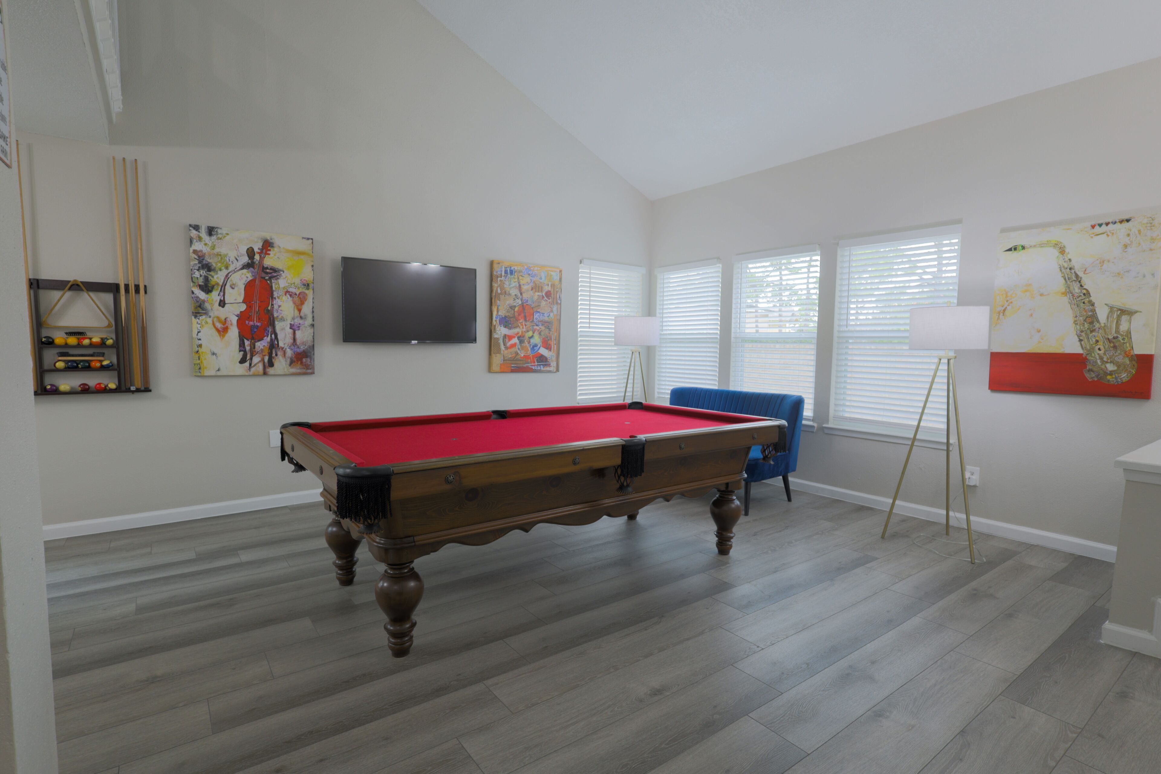 A spacious room with a pool table, artwork on the walls, and a television.