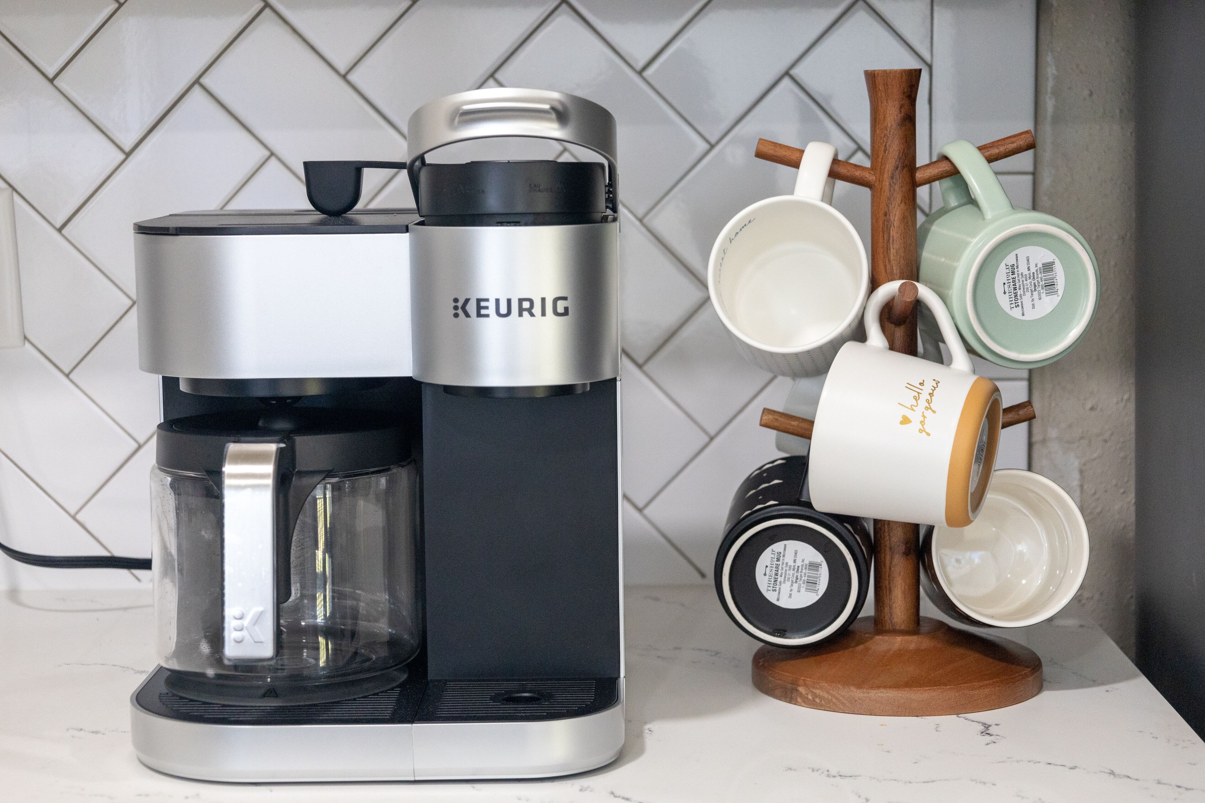 Een Keurig koffiezetapparaat op een aanrecht met een muggenhouder voor verschillende mokken.