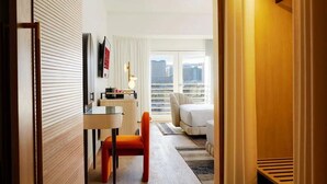 A hotel room with a desk, chair, and a view of the city through large windows. - Beautiful Hotel 2 mins from the strip-The Virgin Hotel- (Las Vegas)