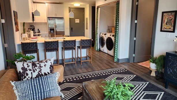 A modern apartment with a kitchen, dining area, and laundry room. It includes a sofa, coffee table, and decorative pillows. - Condo minutes from Broadway (Nashville)