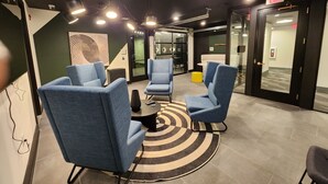 A modern lounge area with blue armchairs, a patterned rug, and a glass door leading to a room. - Condo minutes from Broadway (Nashville)