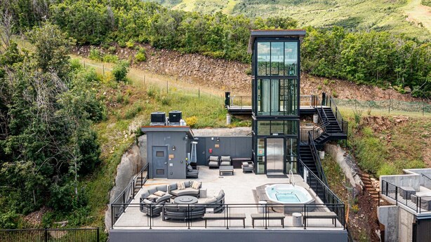 Een modern, meerlaags gebouw met een terras op het dak, zitplaatsen buiten en een jacuzzi.