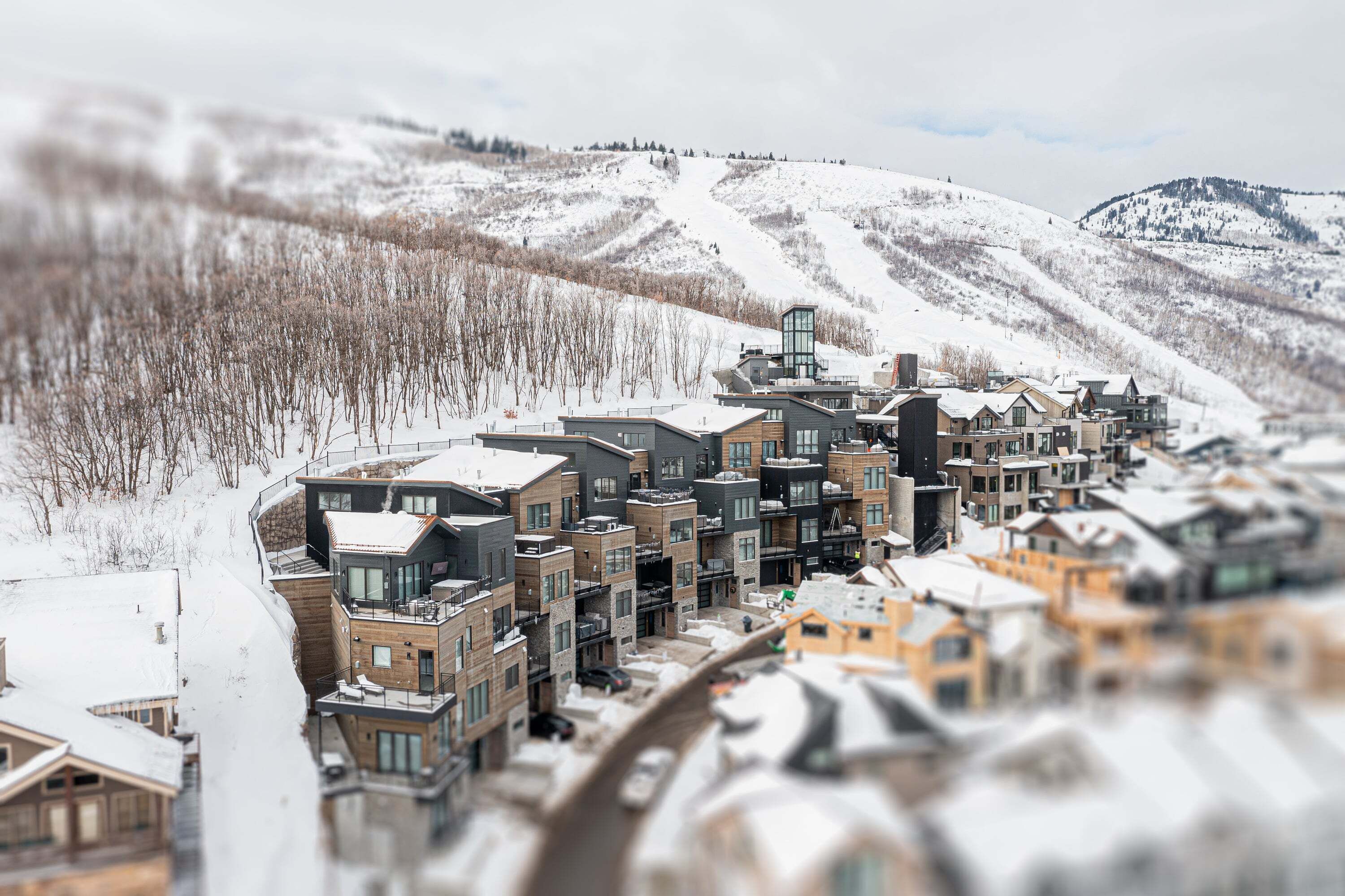 Un moderno resort con edificios de varios pisos, una pista de esquí al fondo y un paisaje cubierto de nieve.