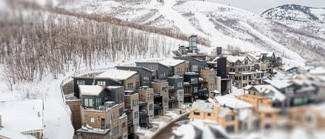 Un moderno resort con edificios de varios pisos, una pista de esquí al fondo y un paisaje cubierto de nieve.