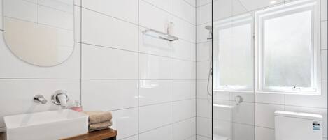 Une salle de bain moderne avec un lavabo blanc, un miroir et un espace douche.