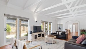 A spacious living room with a large TV, comfortable seating, and a view of the outdoors.