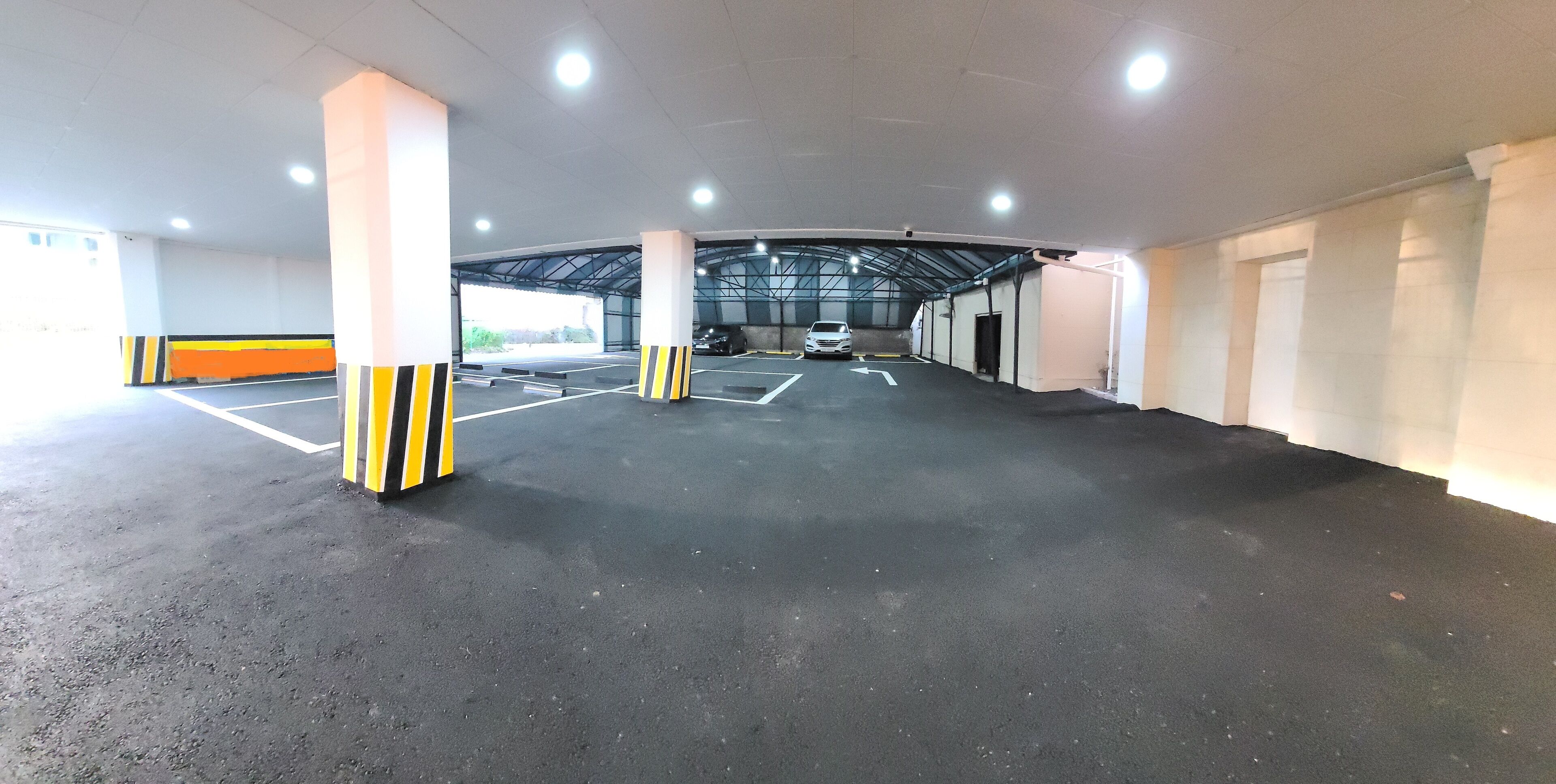 Un estacionamiento interior con múltiples espacios, carriles delimitados y pilares con franjas amarillas y negras.