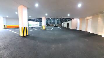 An indoor parking garage with multiple parking spaces, marked lanes, and pillars with yellow and black stripes.