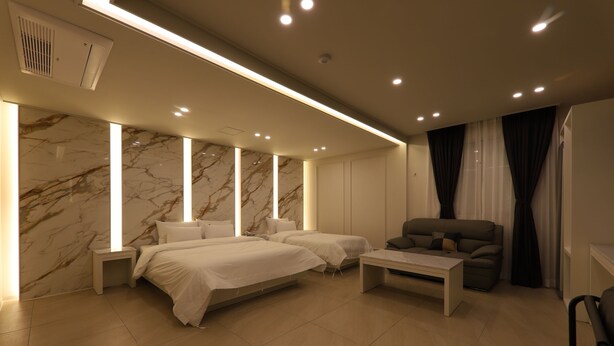 Een moderne hotelkamer met twee bedden, een bank, een salontafel en marmeren muren.