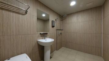 A modern bathroom with a pedestal sink, a mirror, a shower, and a towel rack.