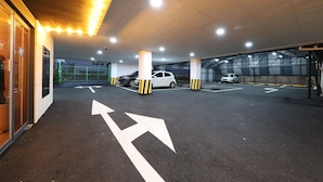Een ondergrondse parkeergarage met pijlen op de vloer, meerdere parkeerplaatsen en een overdekt gebied met kolommen.