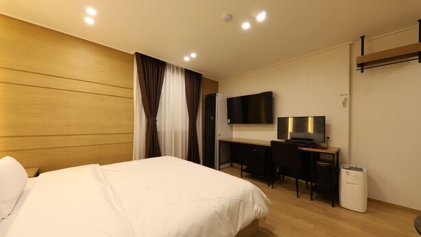 A hotel room with a bed, a desk, a chair, a television, and a white heater. - Hotel Browndot Chungjang (Gwangju)
