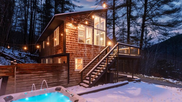 Une cabane en bois avec un jacuzzi, un escalier et des guirlandes lumineuses.