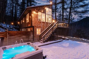 Eine Holzhütte mit Whirlpool, Treppe und Lichterkette.