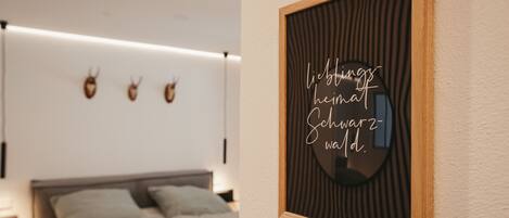 A bedroom with a bed, a nightstand, and a wall-mounted mirror with a decorative frame.