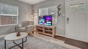 Een woonkamer met een televisie, een bank, een salontafel en een deur.