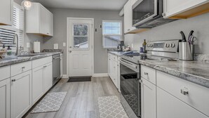 Een moderne keuken met witte kasten, een roestvrijstalen fornuis en een inbouwoven.