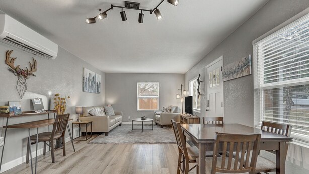 Een ruime woonkamer met een eethoek, een open haard en een groot raam met zonwering.