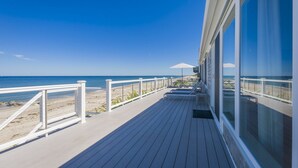 A wooden deck with a railing overlooking a beach. - Oceanfront Property with AC in Scorton Shores (East Sandwich)
