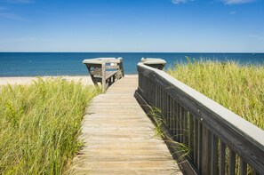 A wooden boardwalk leading to a beach with a clear view of the ocean.
