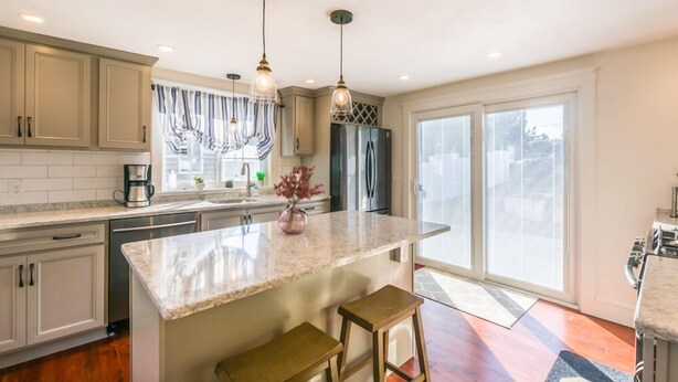 A modern kitchen with a central island, pendant lighting, and a large window providing natural light. - Cape Cod Home—Deck, Near Canal & Bike Path (Sandwich)
