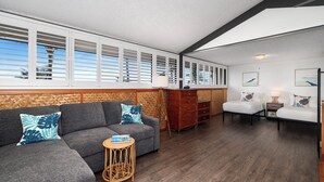 A modern living area with a sofa, armchairs, a small wooden table, and a wooden cabinet.