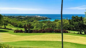 A golf course with a view of the ocean and a hotel in the background.