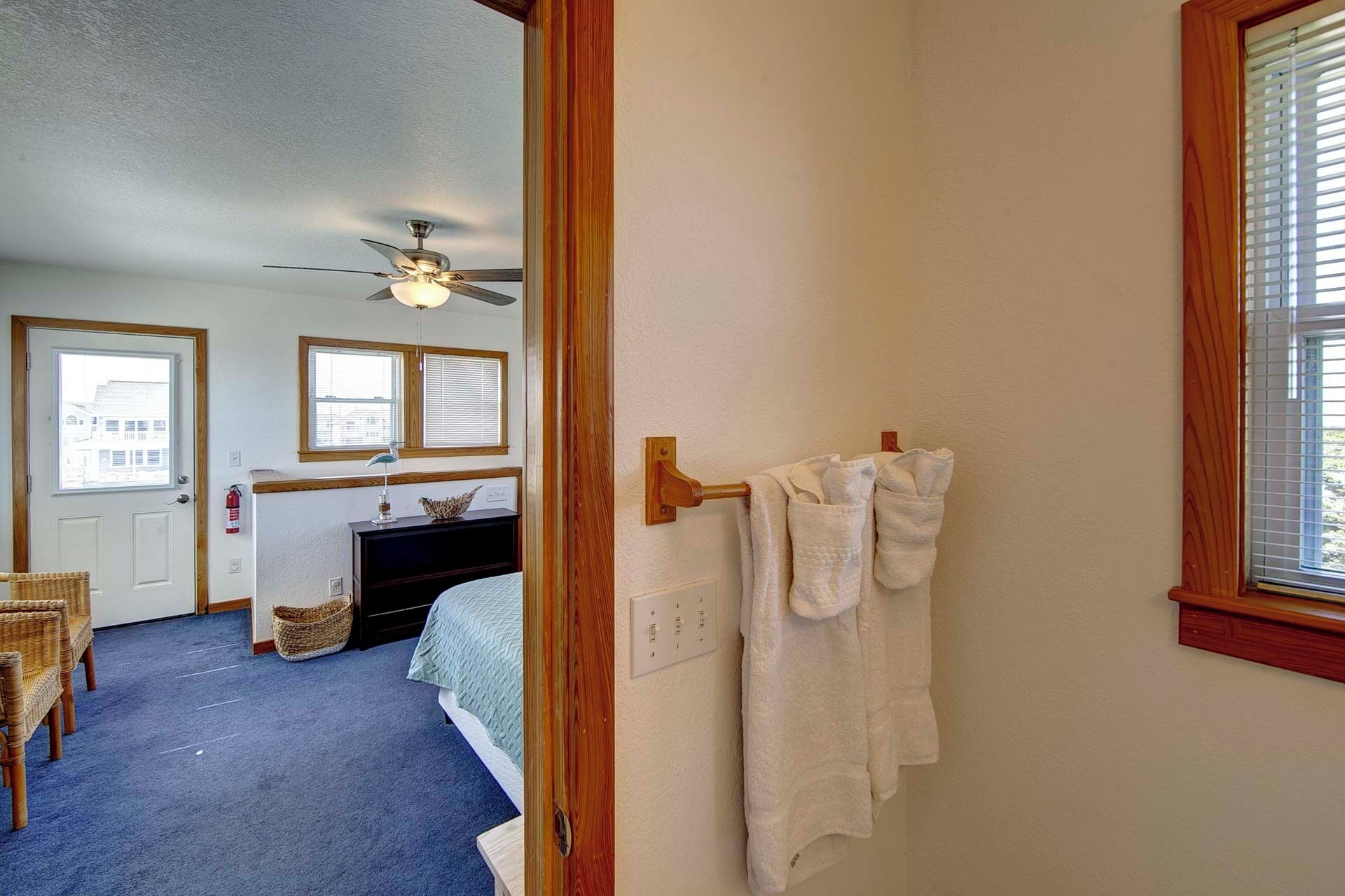 A bedroom with a bed, a ceiling fan, a window, and a door.