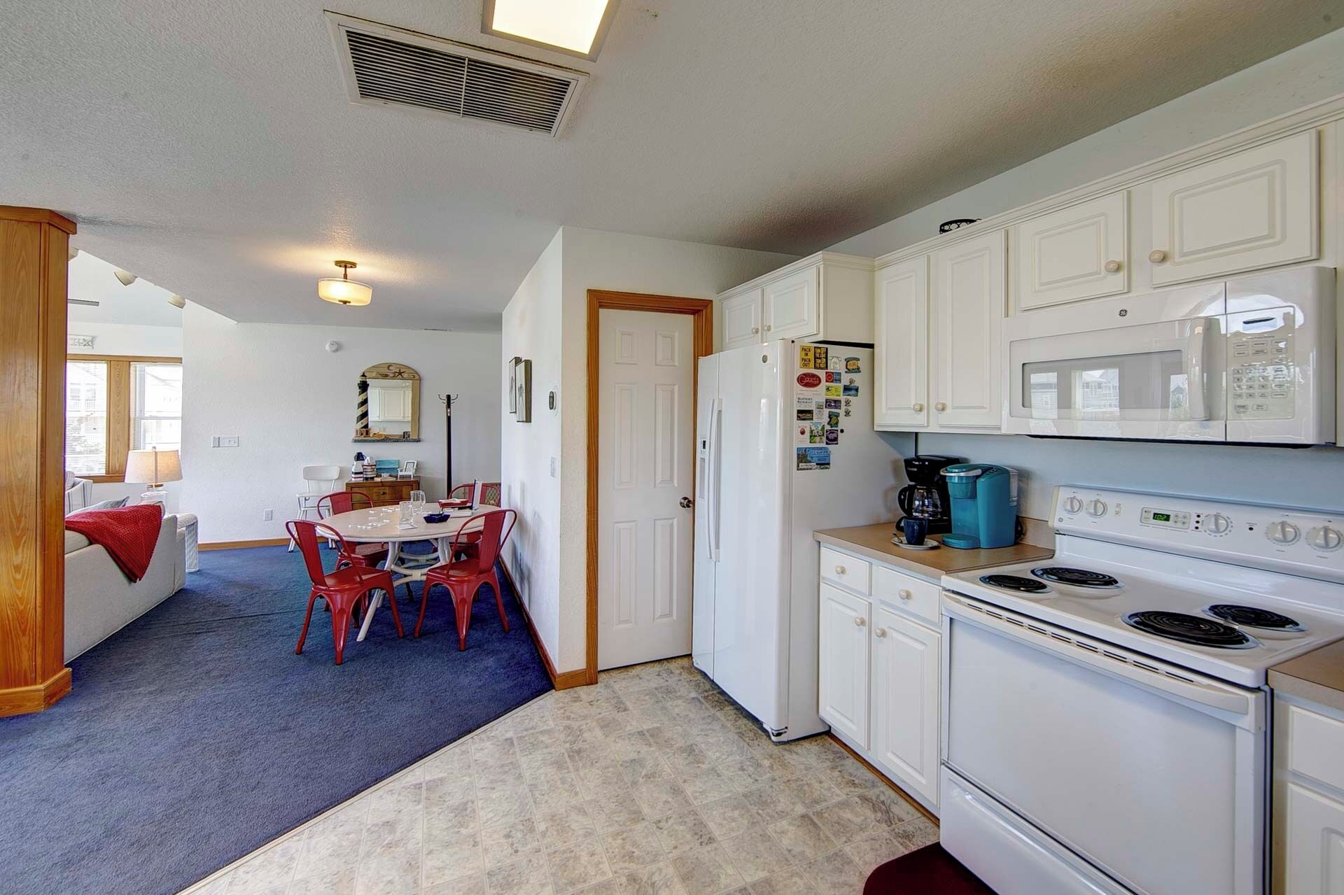 A compact kitchen with white cabinets, a stove, and a microwave.