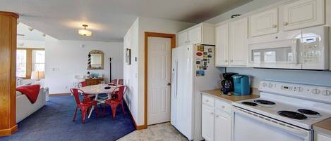 A compact kitchen with white cabinets, a stove, and a microwave.