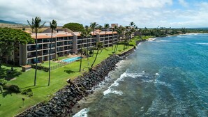 A coastal hotel with multiple balconies, a swimming pool, and a rocky shoreline. - Oceanfront spacious 1bd Maalaea condo (Wailuku)