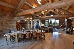A log cabin interior with a dining area, a fireplace, and a stone wall. - Luxury Waterfront Log Home 15 min from Traverse City w/ Dock (Suttons Bay)