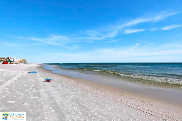 A beach with clear skies, a sandy shore, and a few beach toys.