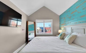 A bedroom with a bed, a window, and a view of buildings outside.