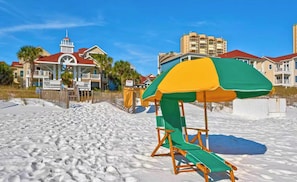 A beach with a lifeguard stand and a building with a red roof in the background.