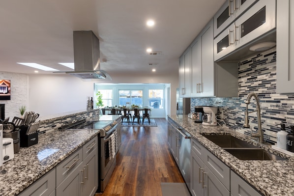 Una cocina moderna con encimeras de granito, electrodomésticos de acero inoxidable y una isla central.