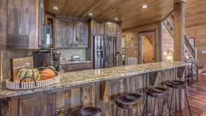 Una cocina rústica con armarios de madera, encimera de granito y refrigerador de acero inoxidable.