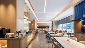 A modern hotel lobby with a reception desk, seating area, and large windows. - REZEN HOTEL (Wuxi)